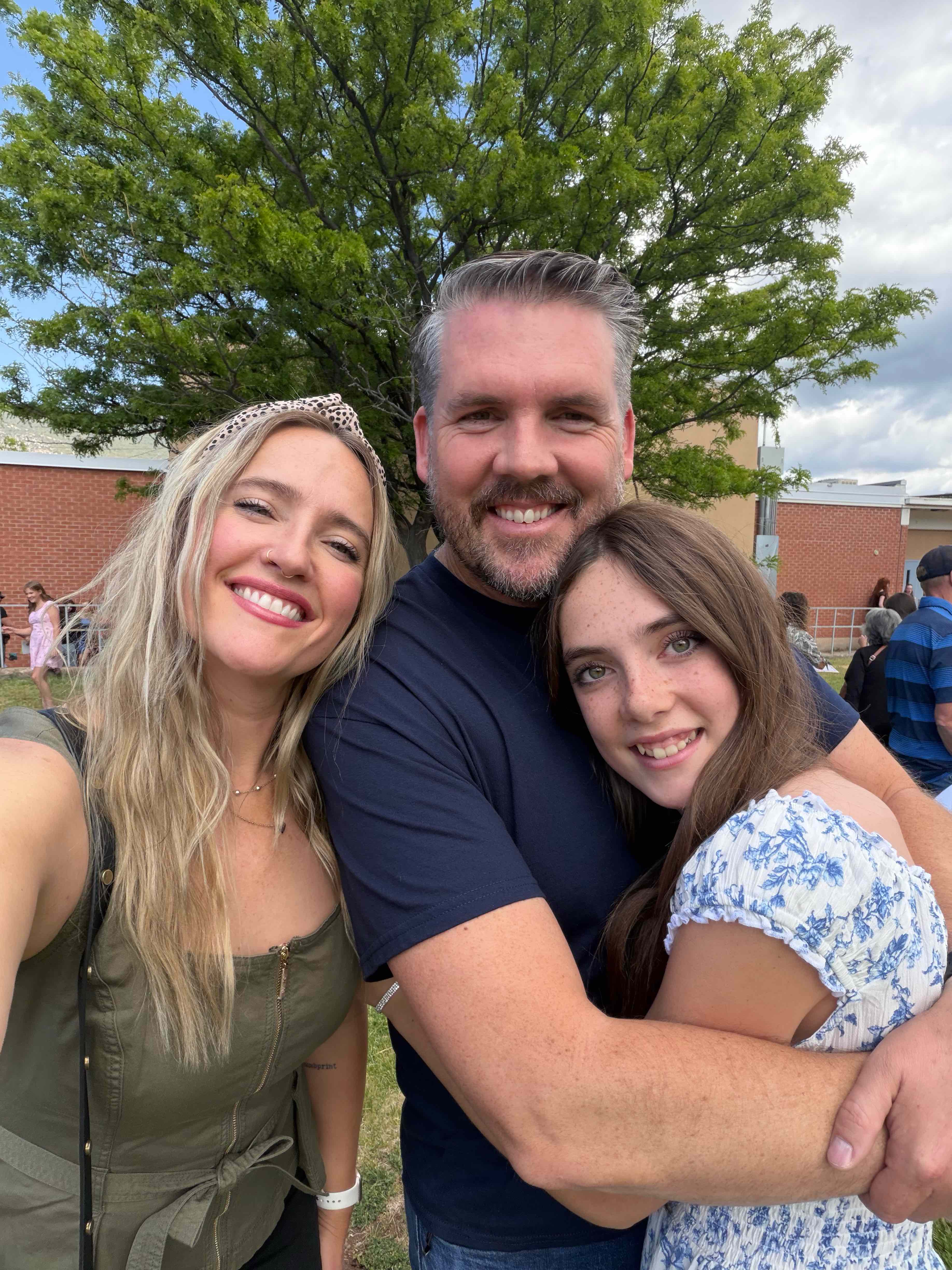 Sailor smiling and hugging her mom and dad outdoors